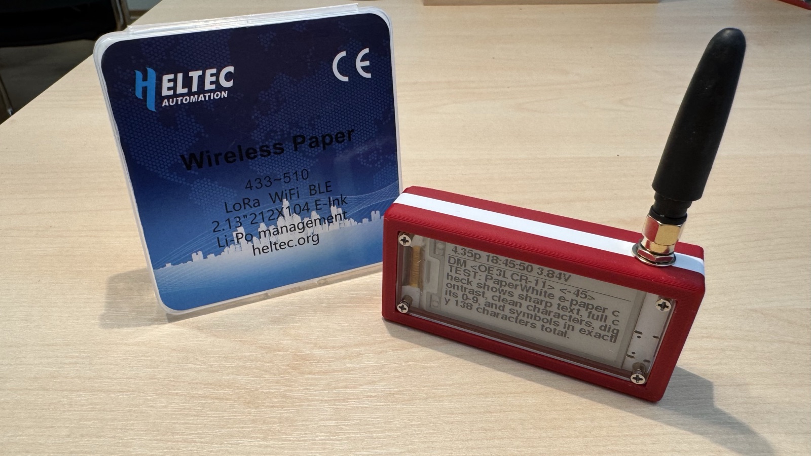 Heltec Wireless Paper im roten 3D-Druck-Gehäuse mit Antenne, daneben die Originalverpackung